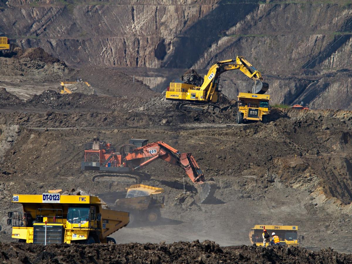 Excavators and a haul truck working at an open-pit mine
